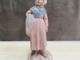 figurine représentant une femme avec un panier, posée sur une table en bois
