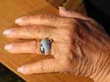 a woman ' s hand with a ring on a bench