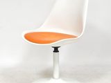 une image représentant une chaise blanche avec une assise orange posée sur une surface blanche