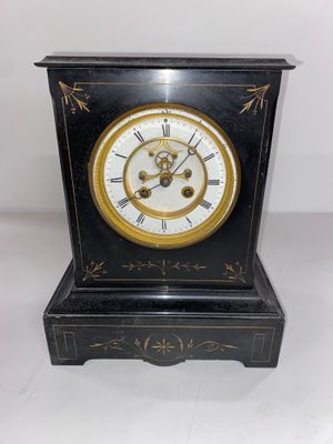 une image représentant une horloge noire et dorée posée sur une table