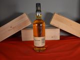 a bottle of whisky sitting on a table next to two wooden boxes