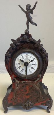 a small clock with a statue on top of it
