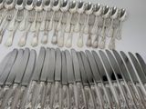 a lot of silver spoons and forks laid out on a table
