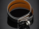 un gros plan sur un bracelet en cuir noir muni d'une boucle en argent