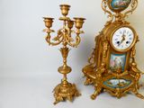 une horloge en or posée à côté d'un candélabre en or