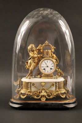 une horloge en or sous un dôme de verre sur une table