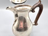 an antique silver coffee pot with a wooden handle on a white background