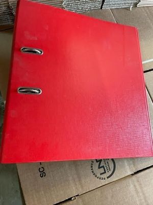 un classeur rouge posé au sommet d'une pile de cartons
