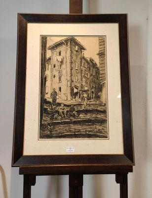 dessin encadré représentant un bâtiment, posé sur un chevalet en bois dans une pièce