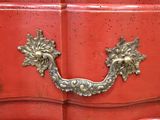 a red chest of drawers with a brass handle on it