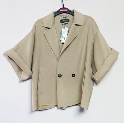 the jacket is tan and has a black button on the front