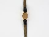 a brown watch with a black strap on a white surface