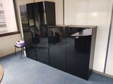 a black cabinet in the corner of a room with blue carpet