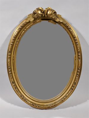 un miroir ovale doré, doté d'un cadre décoratif et orné d'un motif floral