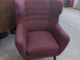 une chaise violette placée dans une pièce où est accroché un tableau au mur