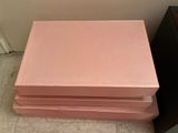 three pink boxes stacked on top of each other on a tiled floor