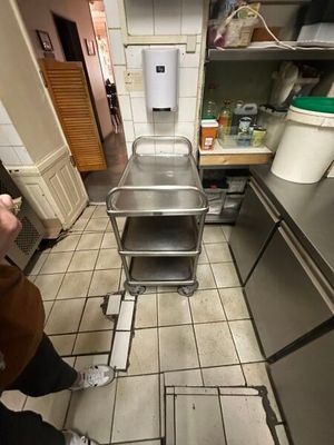 une personne debout dans une cuisine, avec un chariot au milieu de la pièce