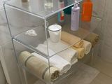une étagère en verre sur laquelle sont posés des serviettes, des savons et d'autres articles