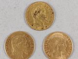three gold coins are shown on a white surface