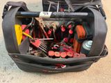 un sac rempli d'outils posé par terre