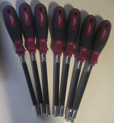 six outils noirs et rouges sont alignés sur une surface blanche