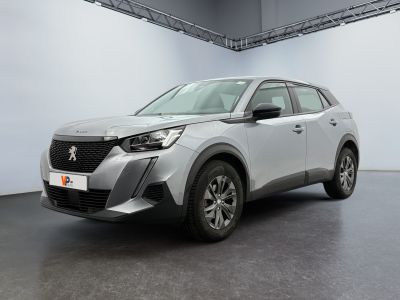 Une voiture argentée est garée dans une grande pièce aux murs blancs.