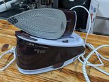 a brown and white steam iron on a wooden table