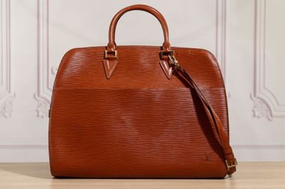 un sac Louis Vuitton marron posé sur une table en bois