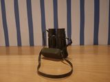 a black camera on a wooden table with a blue and white striped wall behind it