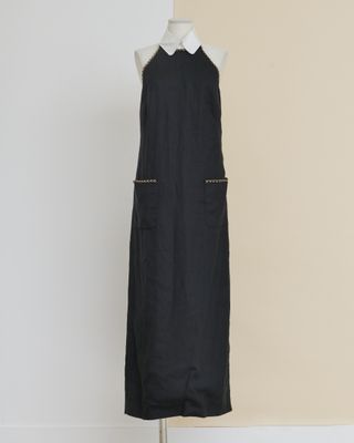 une robe noire posée sur un mannequin adossé à un mur