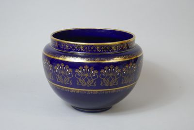 un vase bleu orné de motifs dorés sur un fond blanc