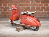 a red scooter sitting next to a red brick wall