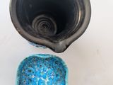 a blue bowl and a black cup on a white table