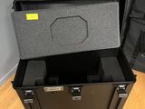 une valise noire posée sur un parquet, à côté d'une autre valise