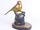 statue of a bird perched on top of a rock on a white surface