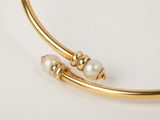 a close up of a gold bracelet with pearls on it