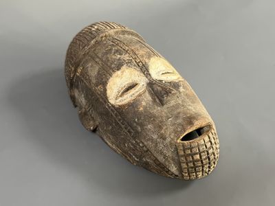 gros plan d'un masque en bois sur une surface grise