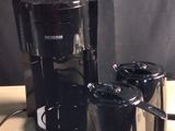 a coffee maker and two cups on a wooden table