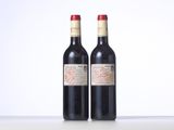 two bottles of red wine sitting on top of a white table