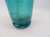 a blue glass vase sitting on top of a white table