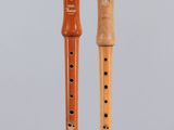 two wooden flutes on display on a clear stand