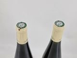 pair of two bottles of wine sitting on top of a white surface