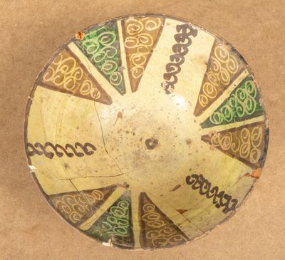 IRAN. Coupe en céramique argileuse à décor en brun et vert.