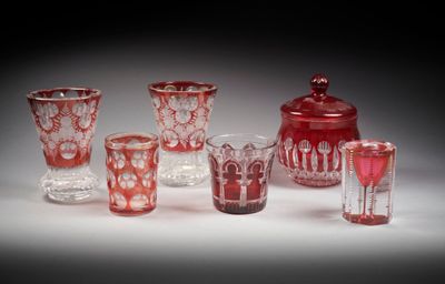 plusieurs vases et verres en verre rouge posés sur une surface blanche