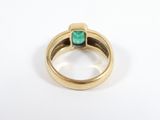 a close up of a gold ring with a green stone