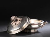 un plat ancien en argent avec un couvercle, posé sur une table