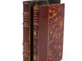 an old book with a brown cover sitting on top of a white surface