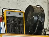 un grand ventilateur posé sur une étagère, à côté d'un radiateur