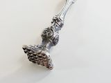 a silver spoon with a bird on it on a white surface
