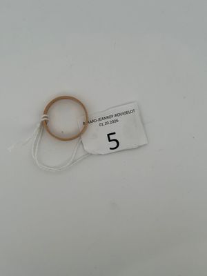 a close up of a ring on a white surface with a tag on it